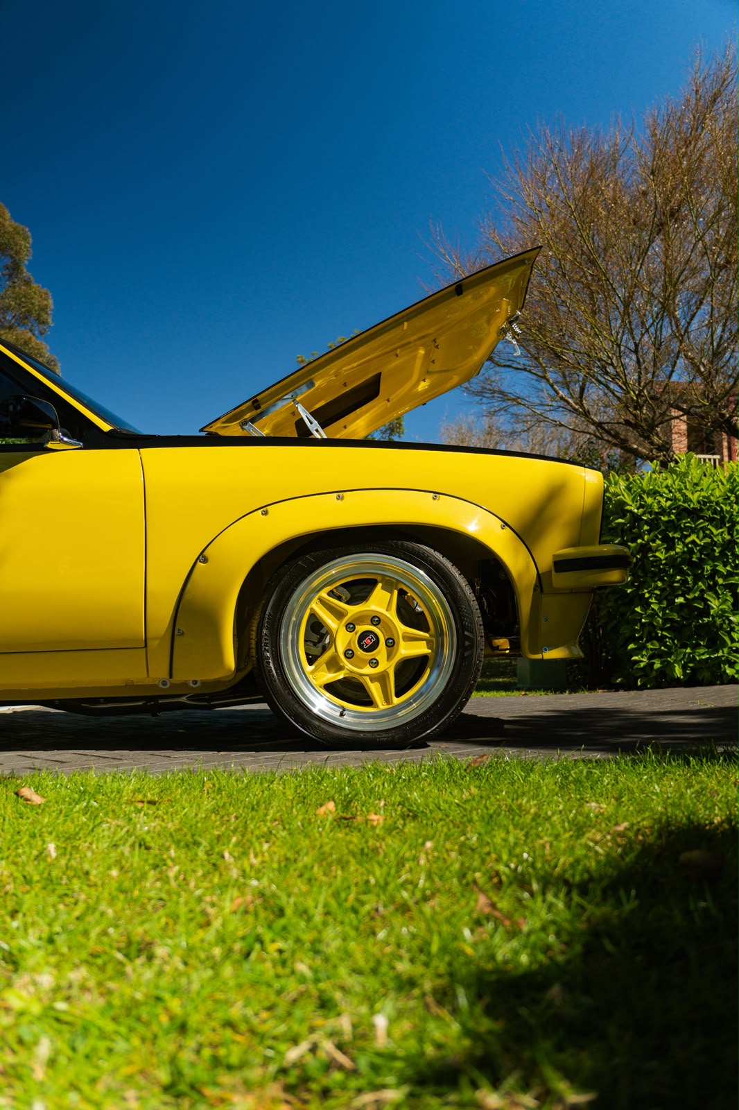 Gloss yellow paint and wheel of a Holden Torana in the sun